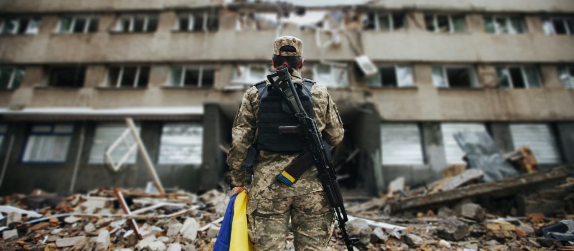 A soldier stands near a destroyed house. War in Ukraine