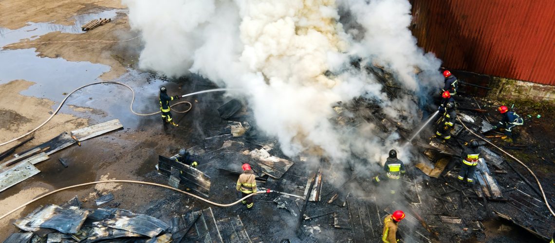 Aerial view of firefighters extinguishing fire in industrial area