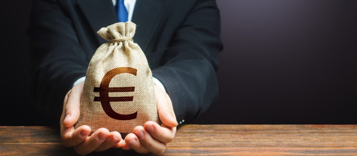 Businessman holds out euro money bag.