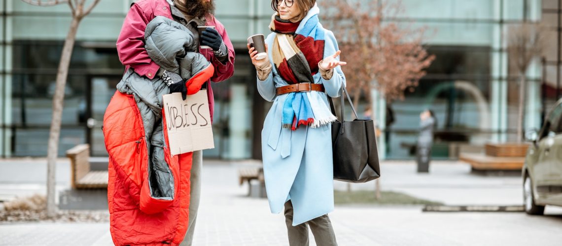 Homeless beggar talking with passing by woman