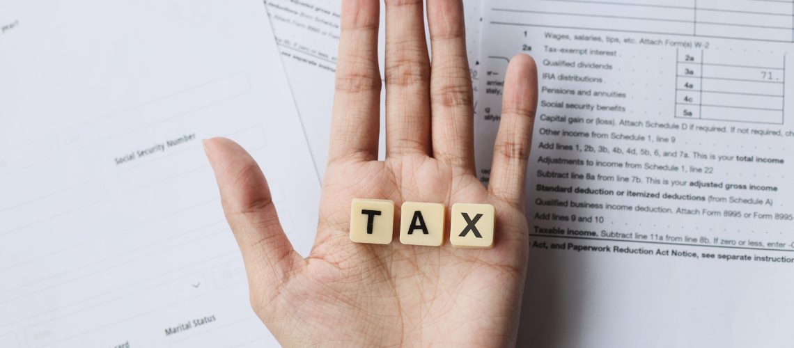 TAX words on palm hands against the tax forms.